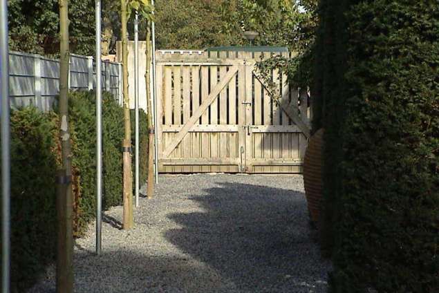 op de achtergrond een hardhouten poort met leiplantanen door a van spelde hoveniers tilburg eindhoven denbosch breburg rijen waspik waalwijk